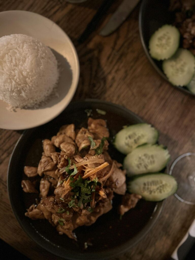Delicious Thai chicken dish served with rice and cucumber slices in a Parisian restaurant.